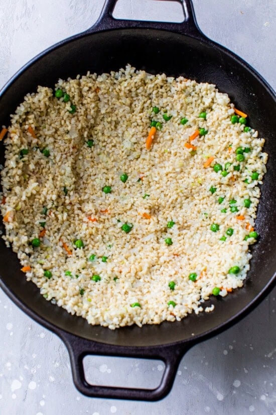 Add rice to wok and flatten