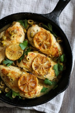 Chicken breasts cooked in a skillet with green olives, lemon and fresh herbs.