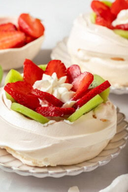 Two pavlova with sliced strawberry and kiwi