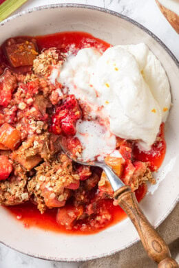 Overhead view of strawberry rhubarb crisp in bowl with whipped cream