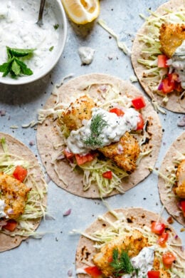 Tzatziki Fish Tacos have a Greek twist! Crisp breaded fish fillets served on tortillas topped with tzatziki sauce made with Greek yogurt, cucumbers and fresh herbs.